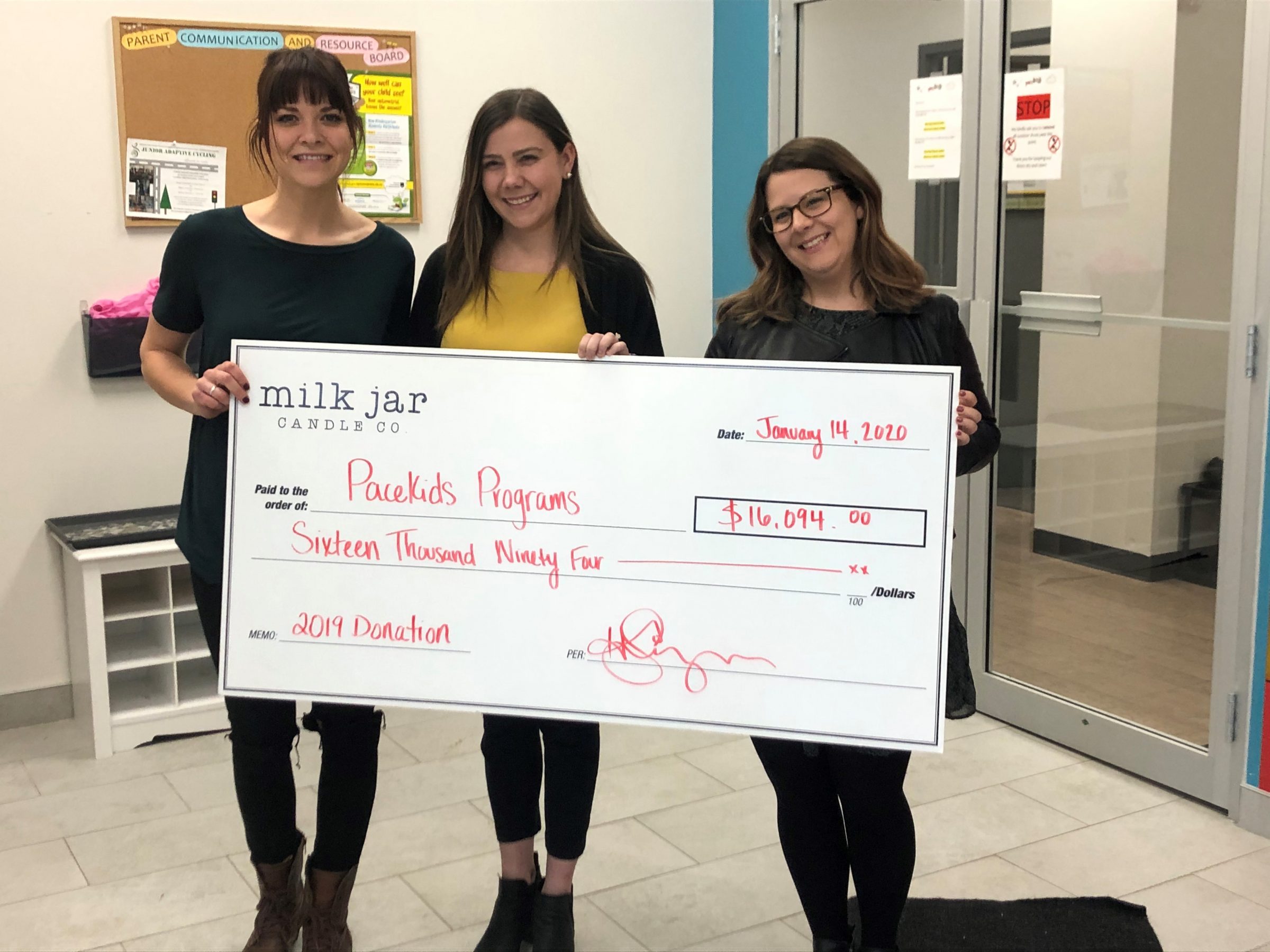 Milk Jar Candle Co & Pacekids Employees hold cheque for special needs program donation