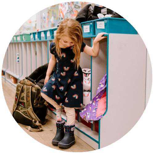 Young girl putting on winter boots outside of her locker