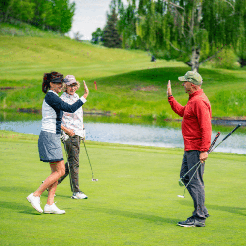 Three golfers on a green walk towards each other to high five